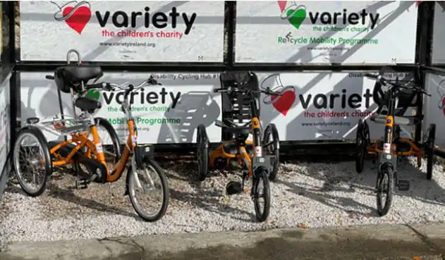 Adaptive tricycles in front of charity signage