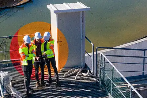 Construction workers reviewing plans on waterfront platform